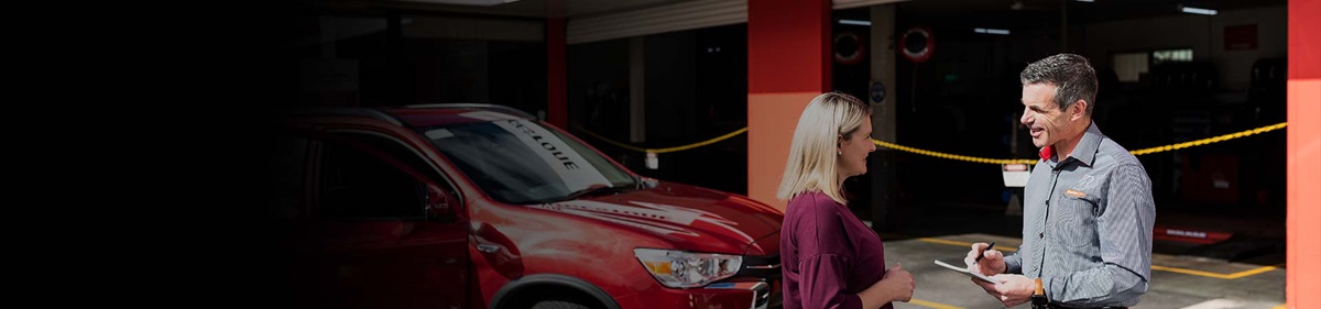 Customer receiving a logbook car service on her vehicle from a qualified mechanic.
