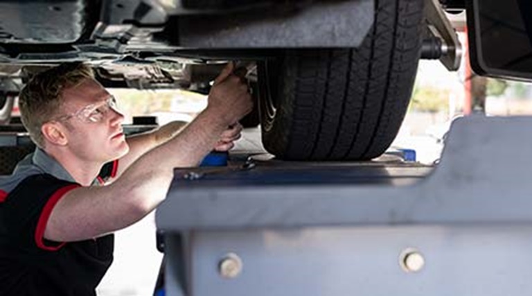 Car repair being completed by a qualified car mechanic servicing a vehicle to ensure car safety. 