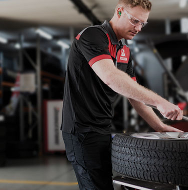 Tyre mechanic servicing a tyre punctured repair on a punctured tyre.